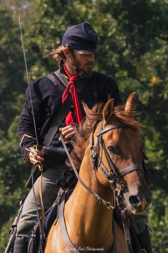 A cavalry soldier on horseback, wielding a saber with a firm grip. Dressed in a traditional military uniform, the soldier's posture is poised and ready, reflecting the agility and combat readiness required in cavalry units. The scene highlights the dynamic and decisive role of cavalry in battle.